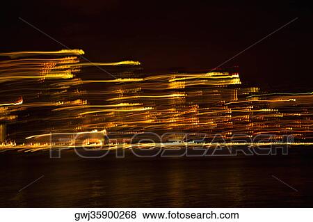 Stock Photo - Skyscrapers at the waterfront lit up at night, New York City, New York State, USA. Fotosearch