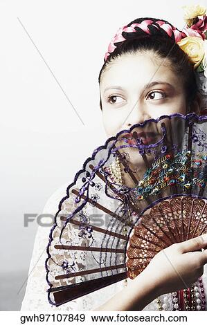 Stock Photo - Teenage girl covering her face with a folding fan. Fotosearch