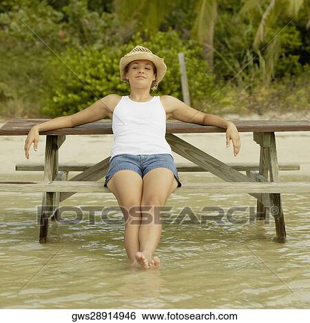 Stock Photograph - Teenage girl sitting on a bench. Fotosearch