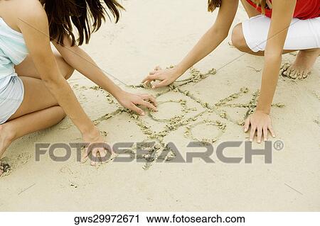 Stock Image - Two girls drawing in sand. Fotosearch