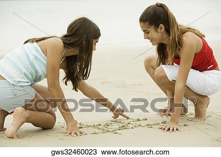 Two girls drawing in sand View Large Photo Image Stock Image - Two girls drawing in sand. Fotosearch