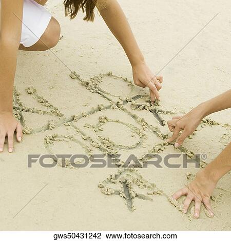 Two girls drawing in sand View Large Photo Image Stock Image - Two girls drawing in sand. Fotosearch