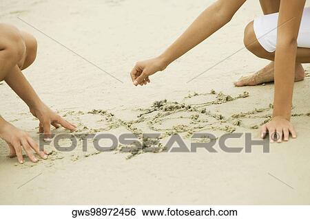 Two girls drawing in sand View Large Photo Image Stock Photograph - Two girls drawing in sand. Fotosearch