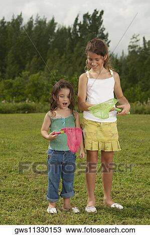 Stock Image - Two girls looking at a butterfly net. Fotosearch