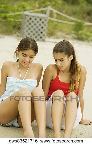 Two girls sitting in sand at the beach View Large Photo Image Stock Photograph - Two girls sitting in sand at the beach. Fotosearch