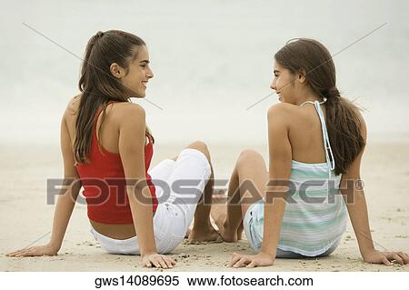 Two girls sitting on the beach laughing View Large Photo Image Stock Photography - Two girls sitting on the beach laughing. Fotosearch