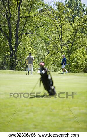 Two men walking on a golf course View Large Photo Image Stock Photograph - Two men walking on a golf course. Fotosearch
