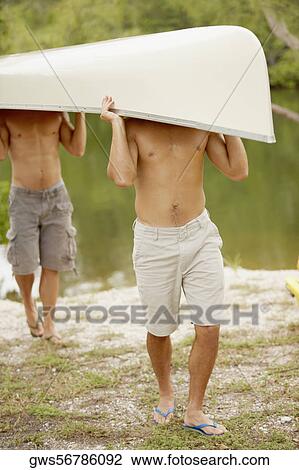 Two mid adult men carrying a canoe on their heads View Large Photo Image Stock Image - Two mid adult men carrying a canoe on their heads. Fotosearch