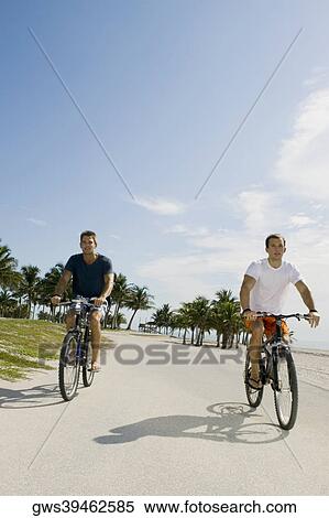Two young men cycling on the road View Large Photo Image Stock Photography - Two young men cycling on the road. Fotosearch