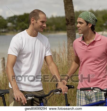 Two young men standing with bicycles View Large Photo Image Picture - Two young men standing with bicycles. Fotosearch