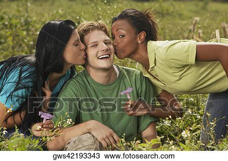 Stock Image - Two young women kissing a young man. Fotosearch