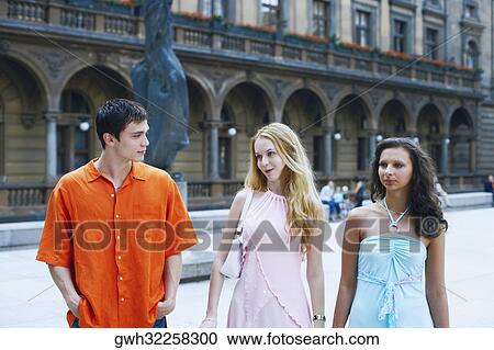 Two young women with a young man walking side by side View Large Photo Image Stock Image - Two young women with a young man walking side by side . Fotosearch