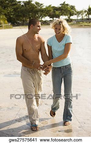 Young couple holding hands walking on the beach View Large Photo Image Stock Image - Young couple holding hands walking on the beach. Fotosearch