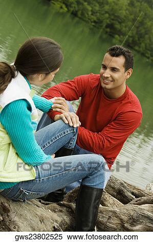 Stock Photography - Young couple sitting at the lakeside. Fotosearch