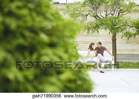 Stock Photograph - Young couple sitting on a bench . Fotosearch