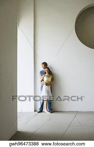Young couple standing against a wall View Large Photo Image Stock Photo - Young couple standing against a wall. Fotosearch