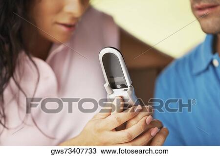 Stock Image - Young man and a young woman holding a mobile phone. Fotosearch