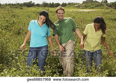 Young man and two young women walking in a field View Large Photo Image Stock Photo - Young man and two young women walking in a field. Fotosearch