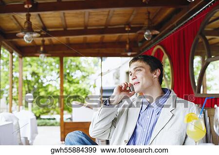 Stock Photo - Young man talking on mobile phone in a restaurant . Fotosearch