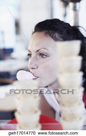 Young woman eating an ice-cream cone View Large Photo Image Stock Image - Young woman eating an ice-cream cone . Fotosearch
