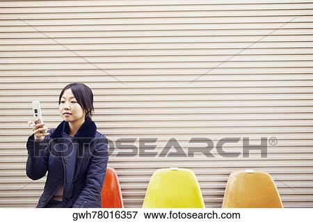 Young woman holding a mobile phone View Large Photo Image Stock Photo - Young woman holding a mobile phone . Fotosearch