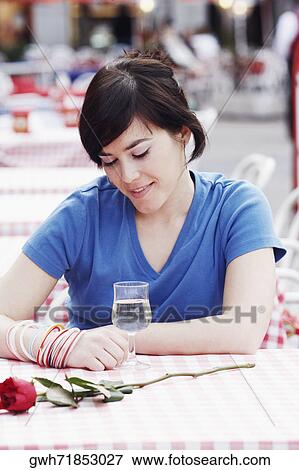 Young woman sitting at a table in a sidewalk cafe View Large Photo Image Stock Photo - Young woman sitting at a table in a sidewalk cafe . Fotosearch