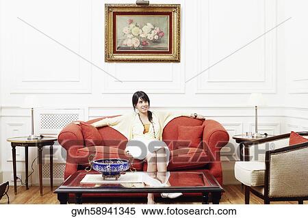 Stock Photography - Young woman sitting on a couch. Fotosearch