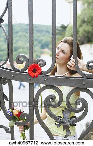 Stock Image - Young woman standing behind a gate . Fotosearch