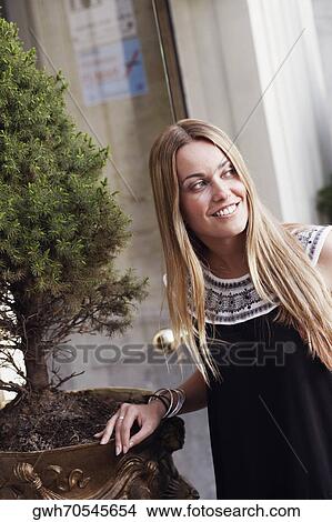 Young woman standing beside a potted plant View Large Photo Image Picture - Young woman standing beside a potted plant . Fotosearch