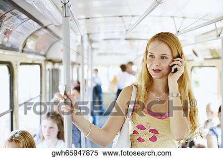Young woman standing in a train and talking on a mobile phone View Large Photo Image Stock Photography - Young woman standing in a train and talking on a mobile phone . Fotosearch