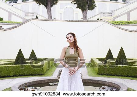 Young woman standing in front of a fountain View Large Photo Image Picture - Young woman standing in front of a fountain . Fotosearch