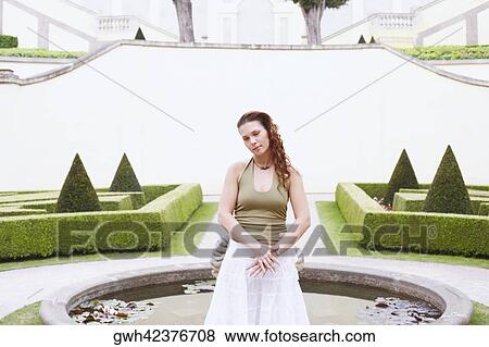 Young woman standing in front of a fountain View Large Photo Image Stock Photo - Young woman standing in front of a fountain . Fotosearch