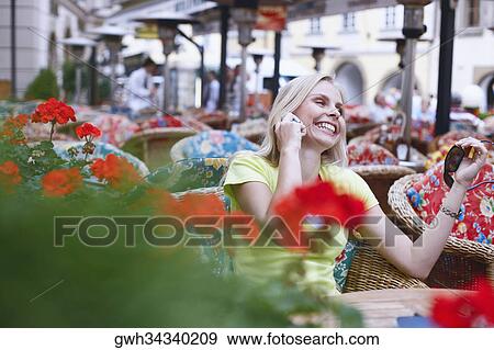 Young woman talking on a mobile phone and sitting in a cafe View Large Photo Image Stock Photo - Young woman talking on a mobile phone and sitting in a cafe . Fotosearch