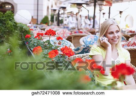 Young woman talking on a mobile phone and sitting in a cafe View Large Photo Image Stock Photo - Young woman talking on a mobile phone and sitting in a cafe . Fotosearch