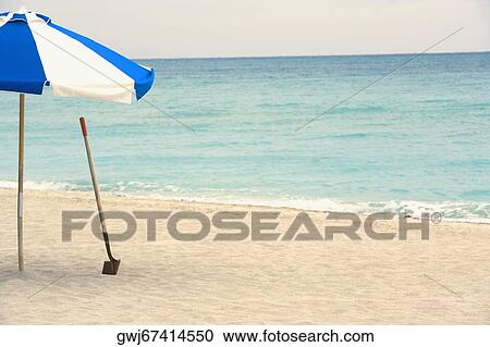 Beach umbrella with a shovel on the beach View Large Photo Image Stock Image - Beach umbrella with a shovel on the beach. Fotosearch