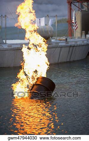 Stock Image - Burning oil drum in water. Fotosearch