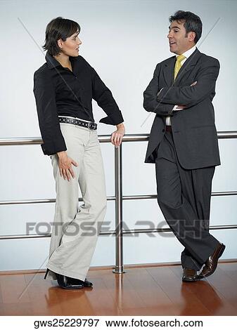 Businessman and a businesswoman leaning against a railing and talking to each other View Large Photo Image Stock Photo - Businessman and a businesswoman leaning against a railing and talking to each other. Fotosearch