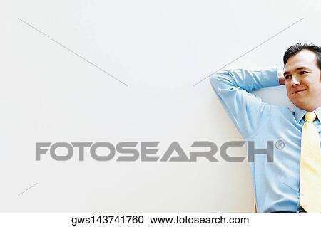 Businessman leaning against a wall and smiling View Large Photo Image Stock Image - Businessman leaning against a wall and smiling. Fotosearch