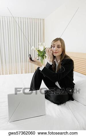 Businesswoman applying makeup with a laptop in front of her View Large Photo Image Stock Image - Businesswoman applying makeup with a laptop in front of her. Fotosearch