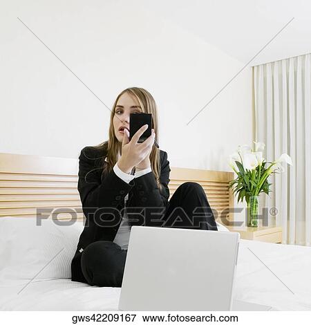 Stock Photo - Businesswoman applying makeup with a laptop in front of her. Fotosearch