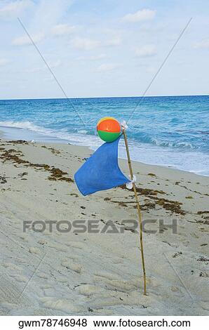 Stock Photo - Close-up of a beach ball and a flag on the beach. Fotosearch