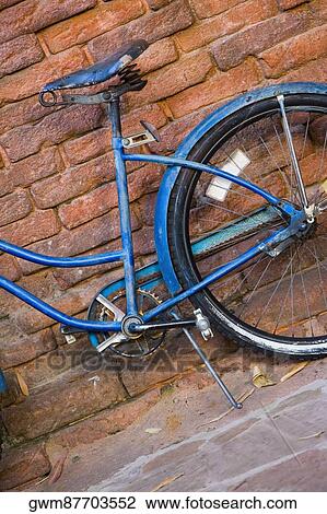 Stock Image - Close-up of a bicycle against a brick wall. Fotosearch