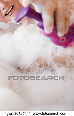 Stock Image - Close-up of a boy holding a soap dispenser in a bathtub. Fotosearch