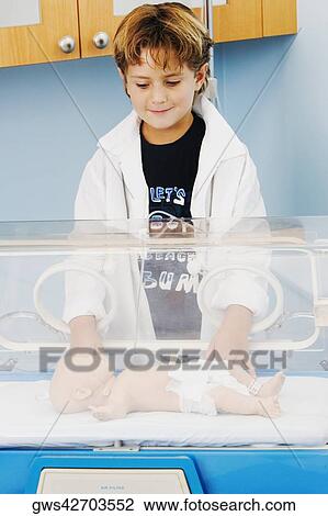 Stock Image - Close-up of a boy standing near an incubator. Fotosearch