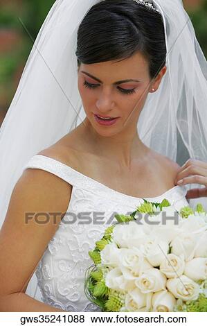 Close-up of a bride holding a bouquet of flowers and looking down View Large Photo Image Stock Photo - Close-up of a bride holding a bouquet of flowers and looking down. Fotosearch