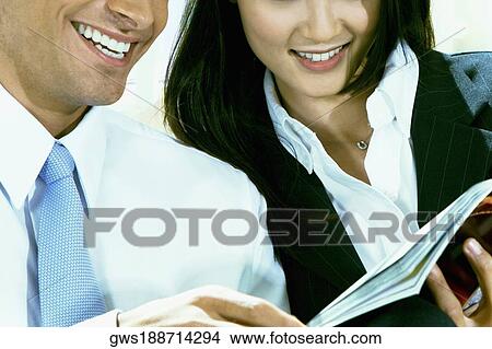 Close-up of a businessman and a businesswoman holding a file View Large Photo Image Picture - Close-up of a businessman and a businesswoman holding a file. Fotosearch