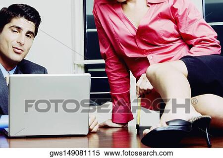 Close-up of a businessman and a businesswoman sitting on a desk View Large Photo Image Stock Photography - Close-up of a businessman and a businesswoman sitting on a desk. Fotosearch