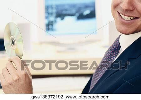 Close-up of a businessman holding a CD and smiling View Large Photo Image Stock Image - Close-up of a businessman holding a CD and smiling. Fotosearch