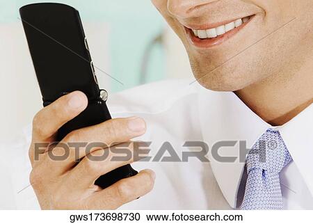 Close-up of a businessman holding a mobile phone and smiling View Large Photo Image Stock Image - Close-up of a businessman holding a mobile phone and smiling. Fotosearch