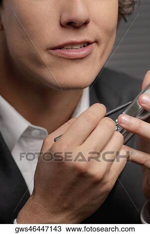 Stock Image - Close-up of a businessman operating a hand held device with a digitized pen. Fotosearch